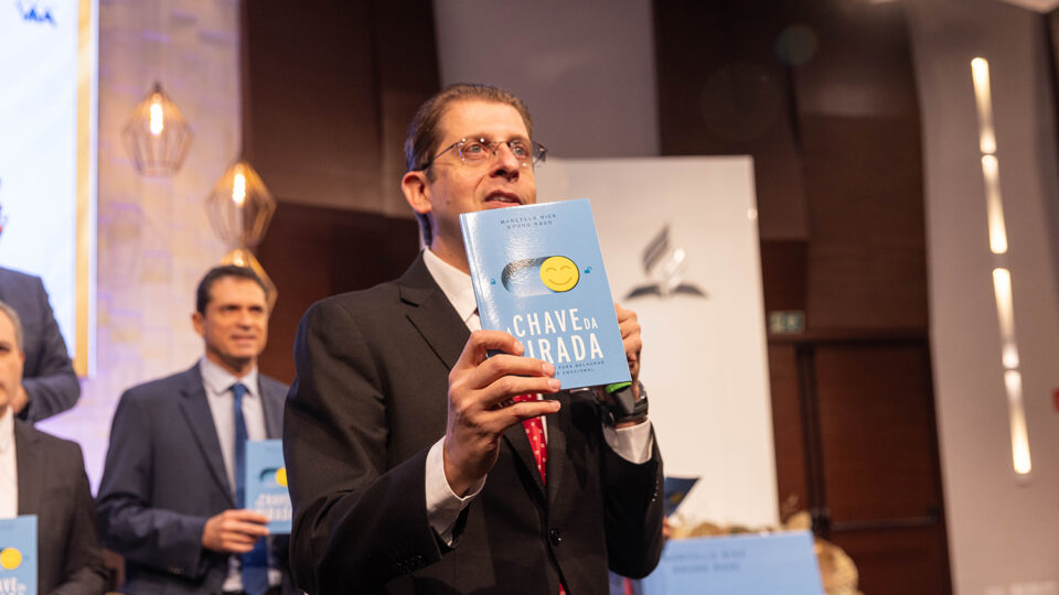 Com o livro em mãos, pastor Rafael Rossi apresenta um dos exemplares aos participantes da Comissão Diretiva Plenária (Foto: Gustavo Leighton)